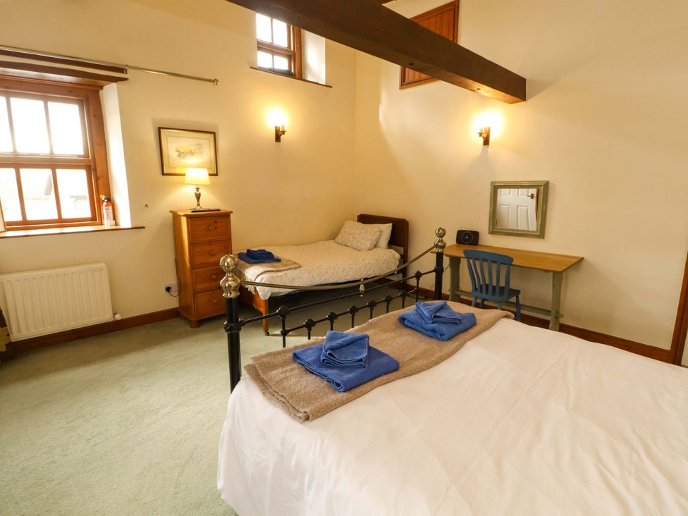 A bedroom with two beds and a desk at High Mill House in Penrith