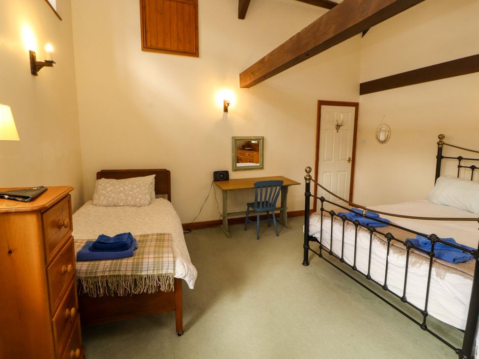A bedroom with two beds and a desk at High Mill House in Penrith