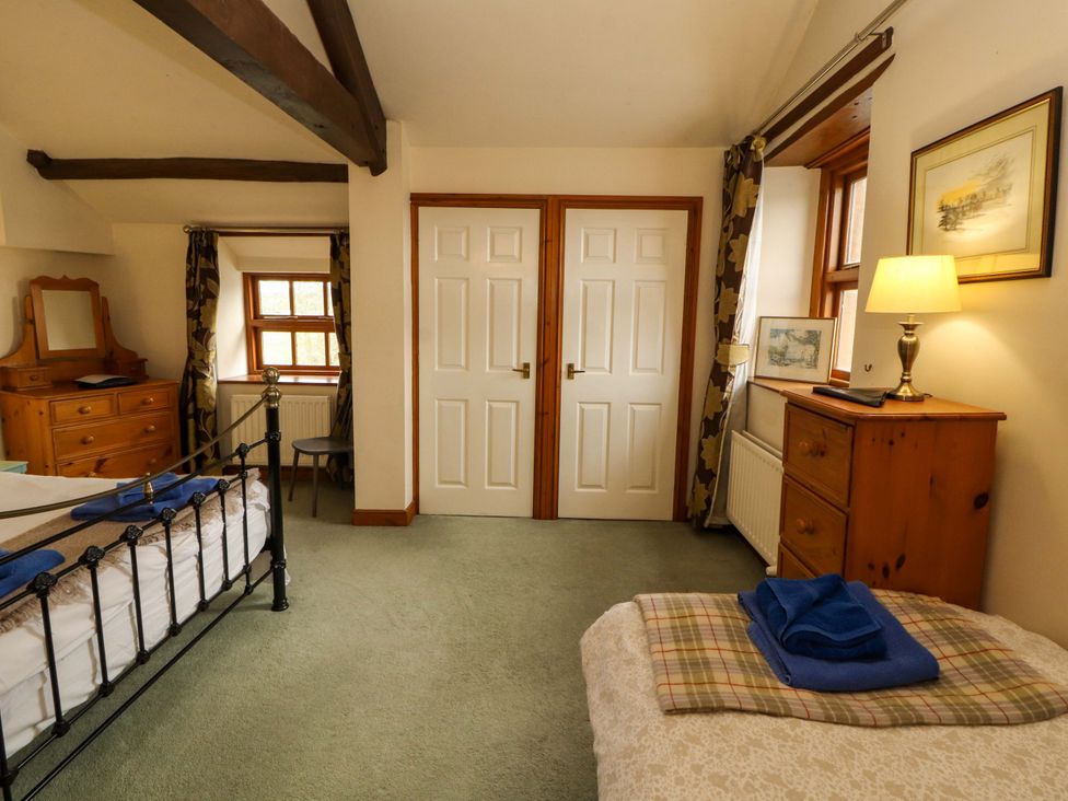 A bedroom with a bed, dresser, and window at High Mill House in Penrith