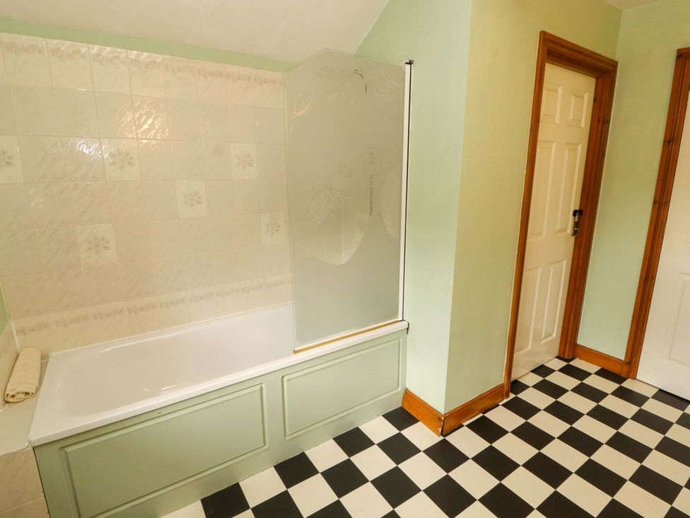 A bathroom with a bathtub and shower screen at High Mill House in Penrith
