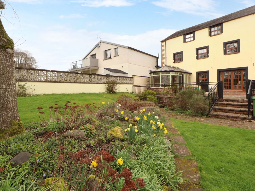 A garden with flowers and a house in the background at High Mill House Penrith