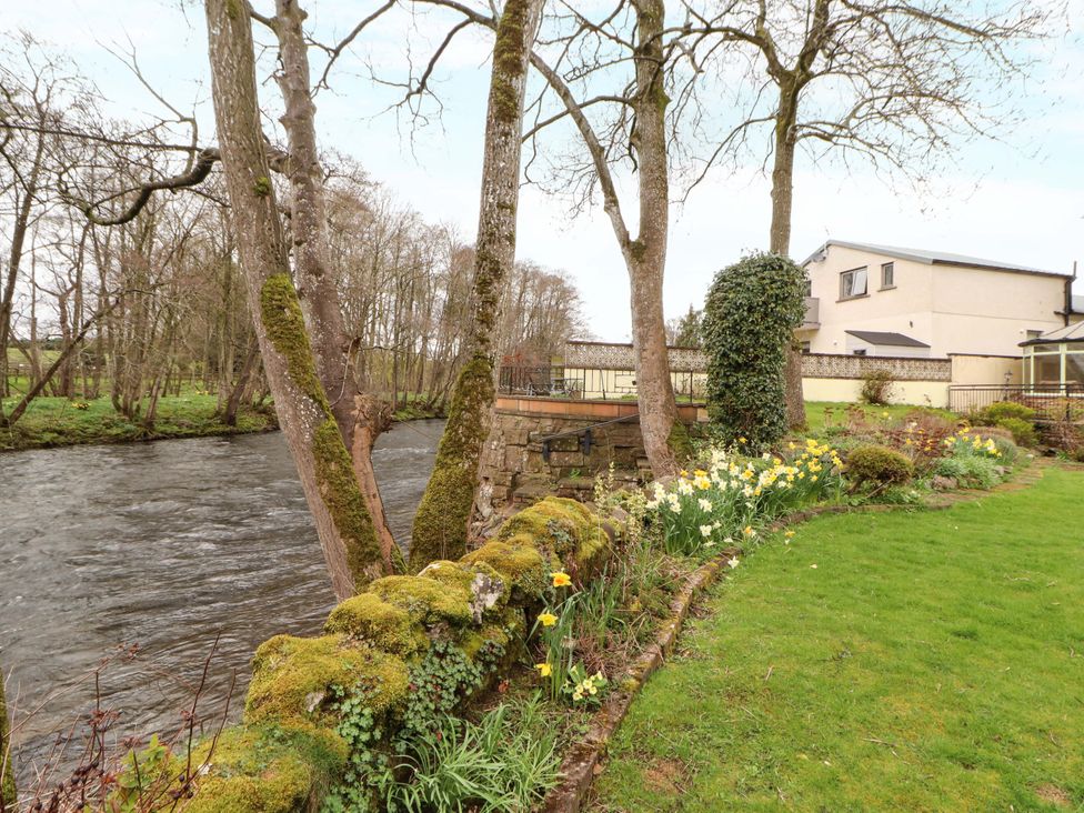 A garden with a river and trees at High Mill House Penrith