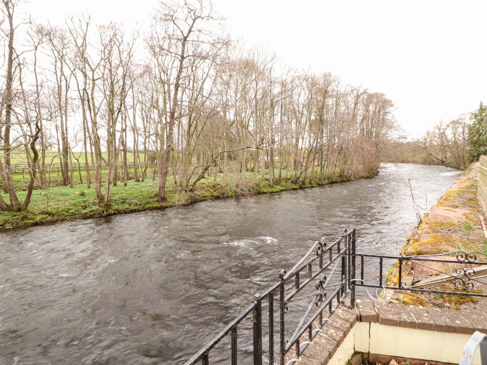 A view of a river with trees along the bank at High Mill House Penrith