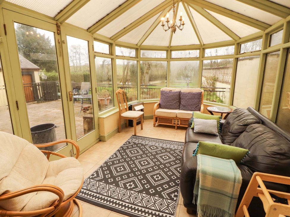 A conservatory with seating and a rug at High Mill House Penrith