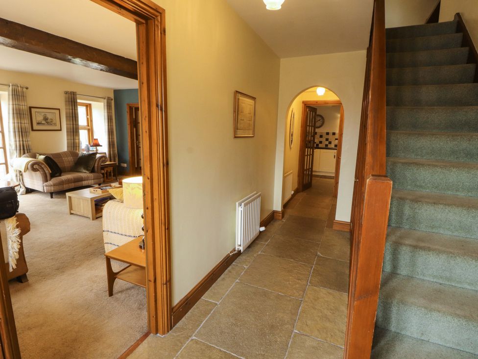 A hallway with a staircase and access to a living room at High Mill House in Penrith