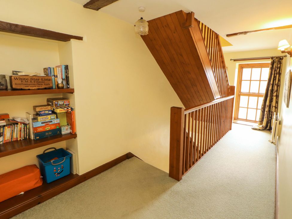A hallway with a bookshelf and stairs at High Mill House Penrith