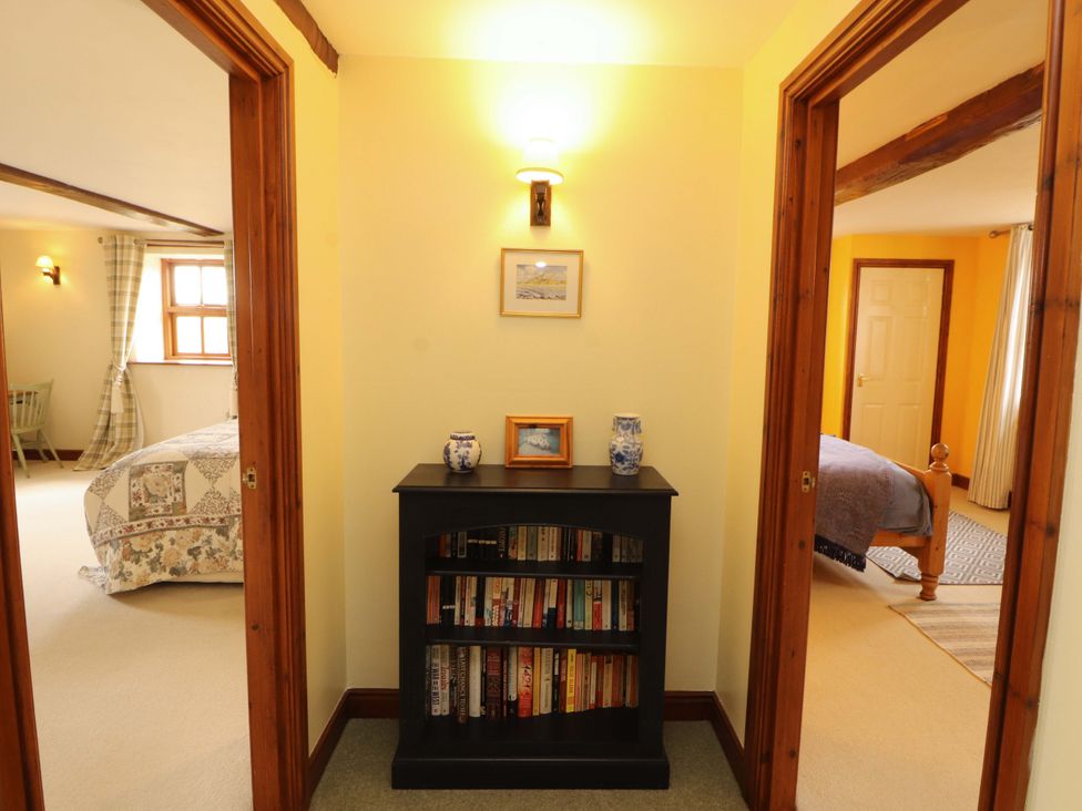 A hallway with a bookshelf and doorways at High Mill House in Penrith