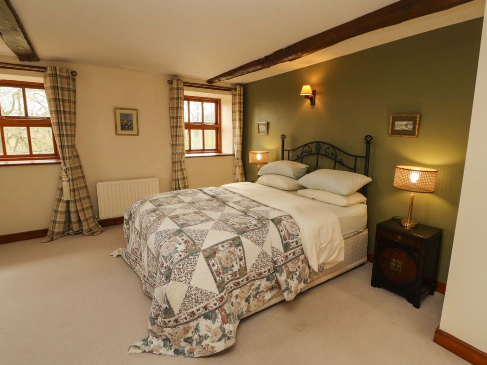 A bedroom with a bed and two windows at High Mill House in Penrith