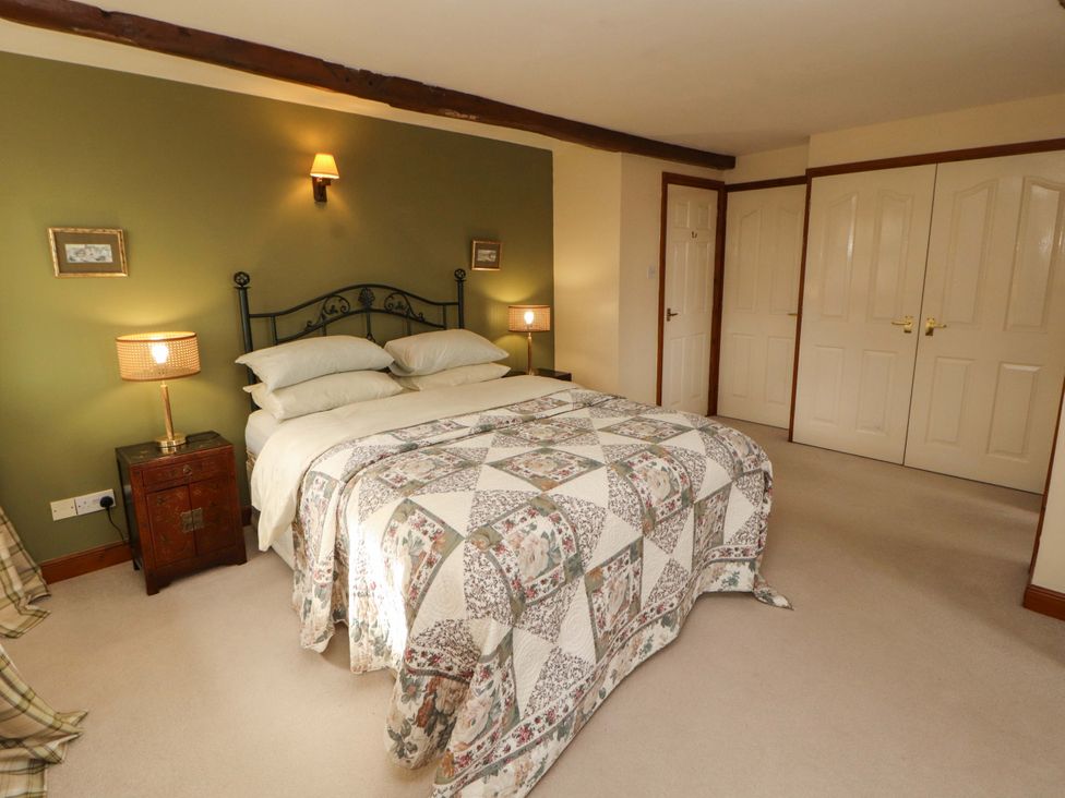 A bedroom with a bed and bedside table at High Mill House in Penrith