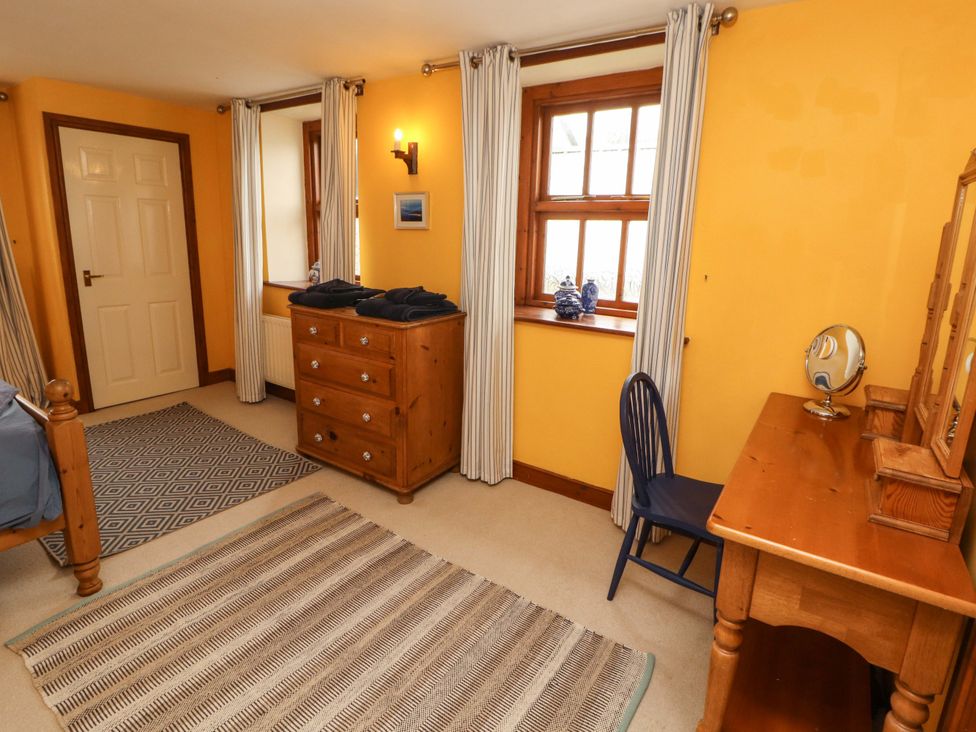 A bedroom with a bed, dresser, and chair at High Mill House in Penrith