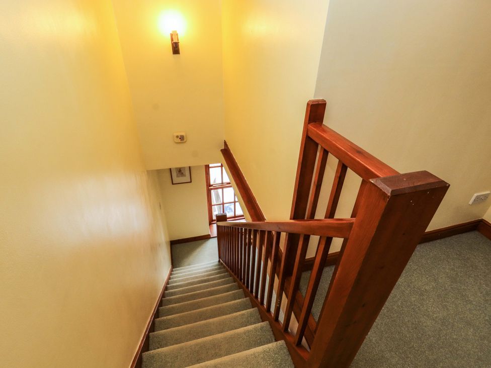 A staircase with wooden railing and light fixture at High Mill House Penrith