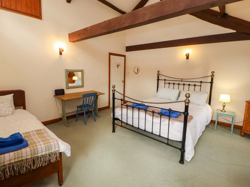 A bedroom with two beds and a desk at High Mill House in Penrith