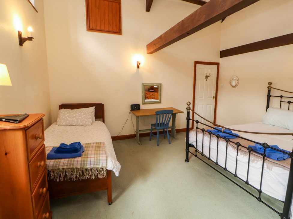 A bedroom with two beds and a desk at High Mill House in Penrith