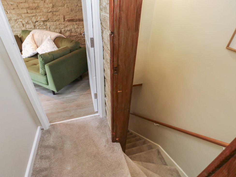 A staircase leading down to a room with a green sofa at Riverview Cottage in Holmfirth