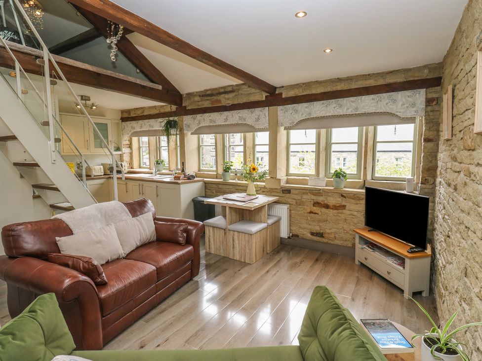 A living room with a sofa and dining table at Riverview Cottage Holmfirth