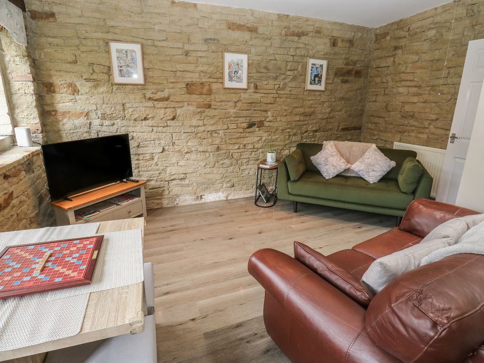 A living room with a television and seating at Riverview Cottage in Holmfirth