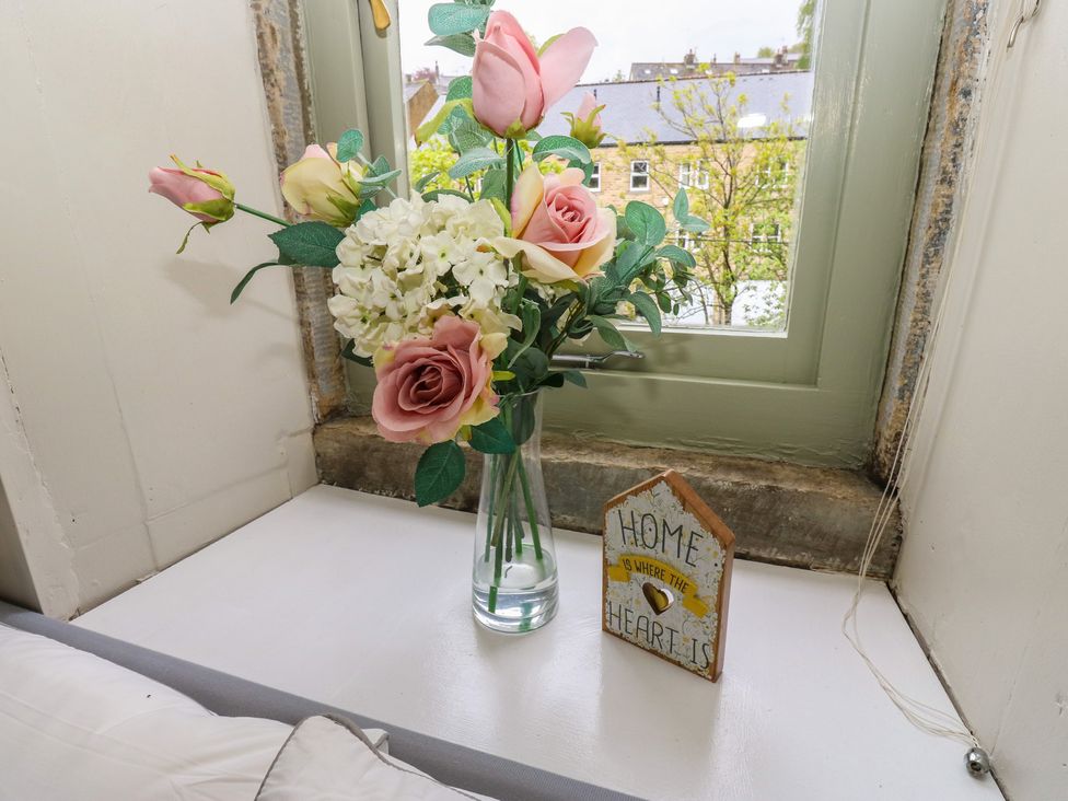 A flower vase and decorative sign on a windowsill at Riverview Cottage Holmfirth