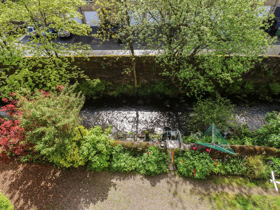 A garden with flowers and a stream at Riverview Cottage Holmfirth