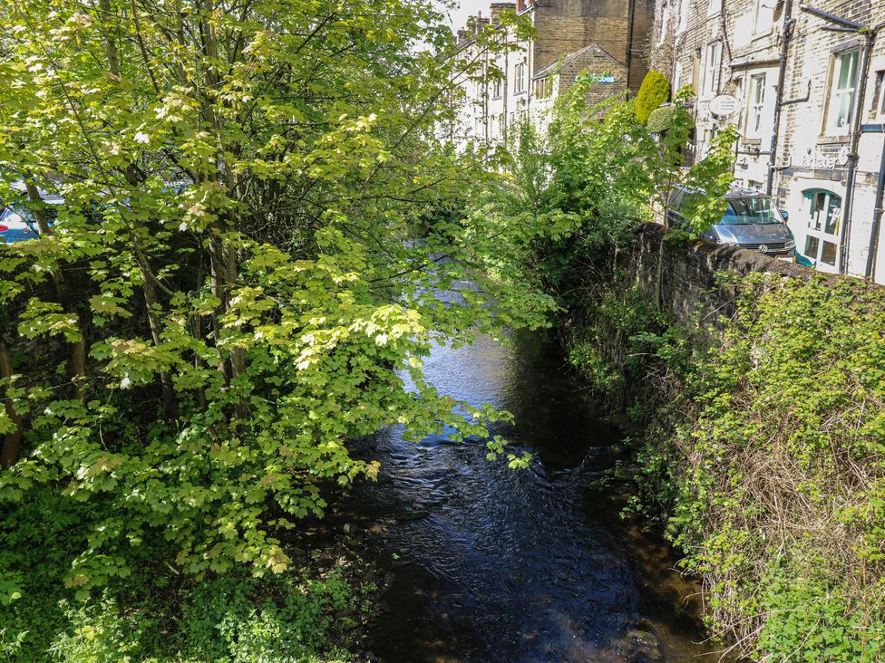 A river surrounded by trees and buildings at Riverview Cottage Holmfirth