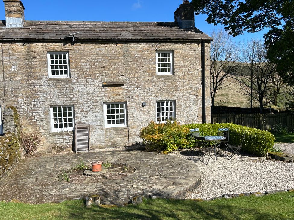An outdoor area with a stone house and patio furniture at Tarn House in Hawes