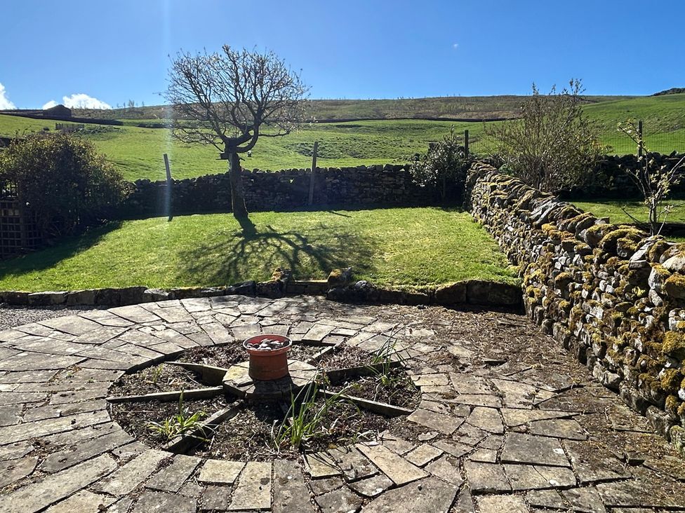 A garden with a tree and stone wall at Tarn House in Hawes