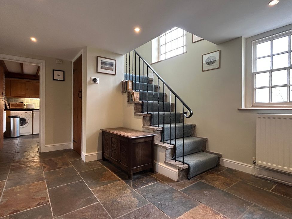 A hallway with a staircase and console table at Tarn House in Hawes