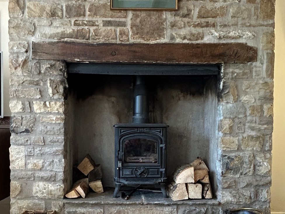 A fireplace with a wood stove and logs at Tarn House in Hawes