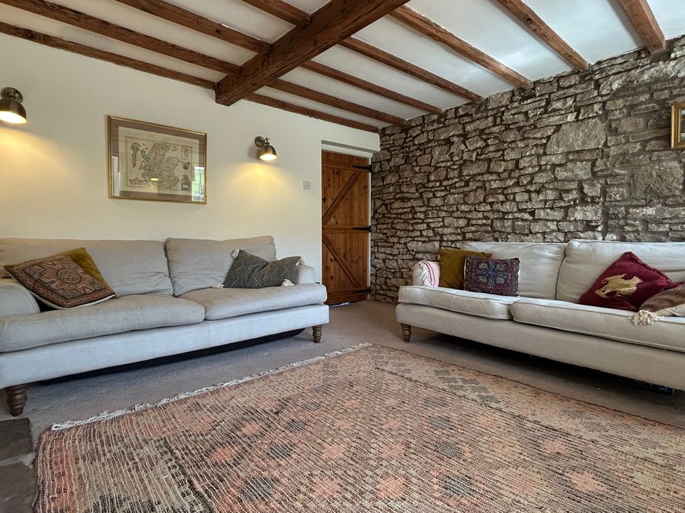 A living room with sofas and a stone wall at Tarn House in Hawes
