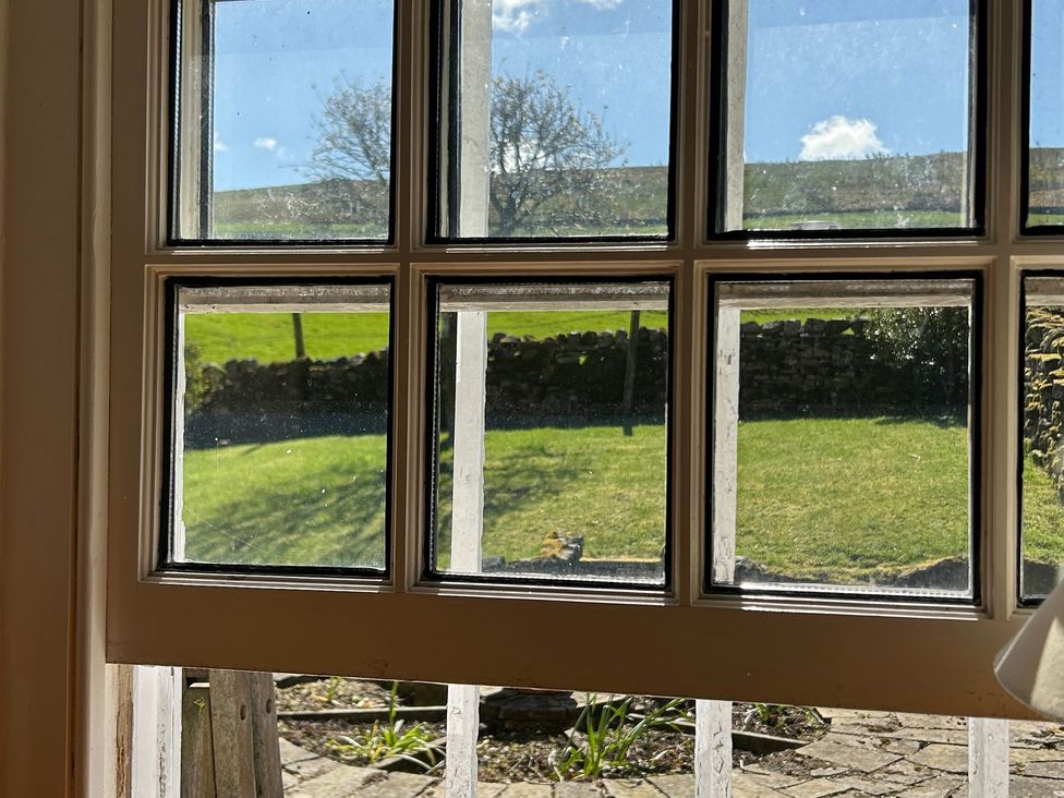 A window with a view of grass and stone wall at Tarn House in Hawes