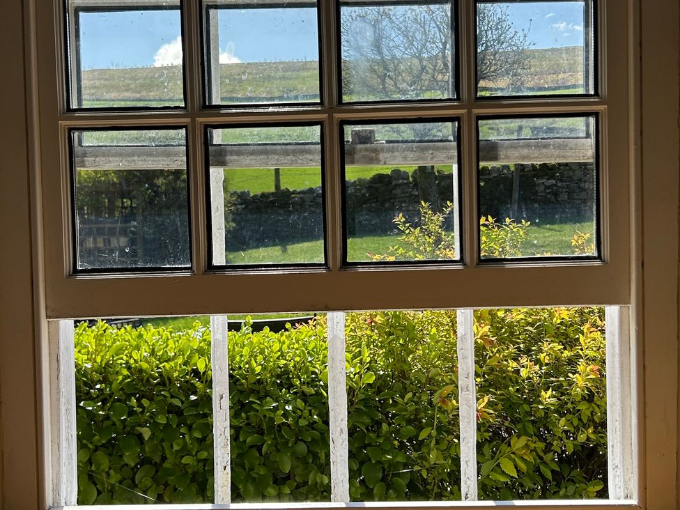 A view from a window showing greenery and a stone wall at Tarn House in Hawes
