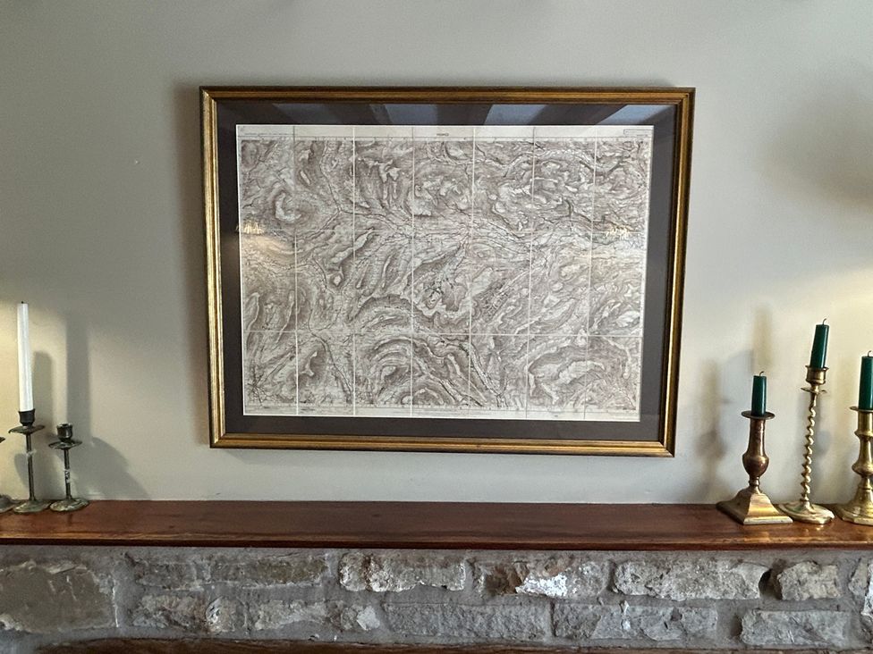 A framed artwork above a stone mantel in the living room at Tarn House in Hawes