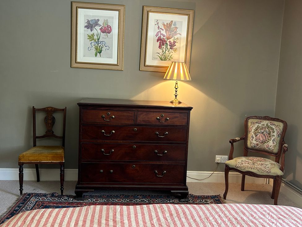 A bedroom with a dresser, lamp, and two chairs at Tarn House in Hawes
