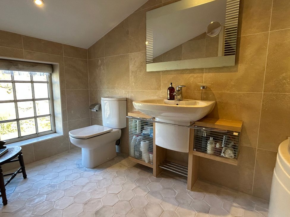 A bathroom with a sink, toilet, and storage unit at Tarn House in Hawes