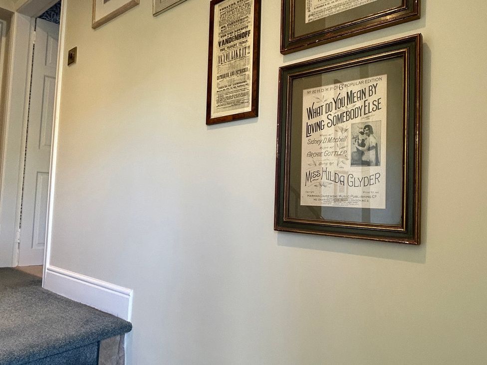 A hallway with framed pictures and a staircase at Tarn House in Hawes