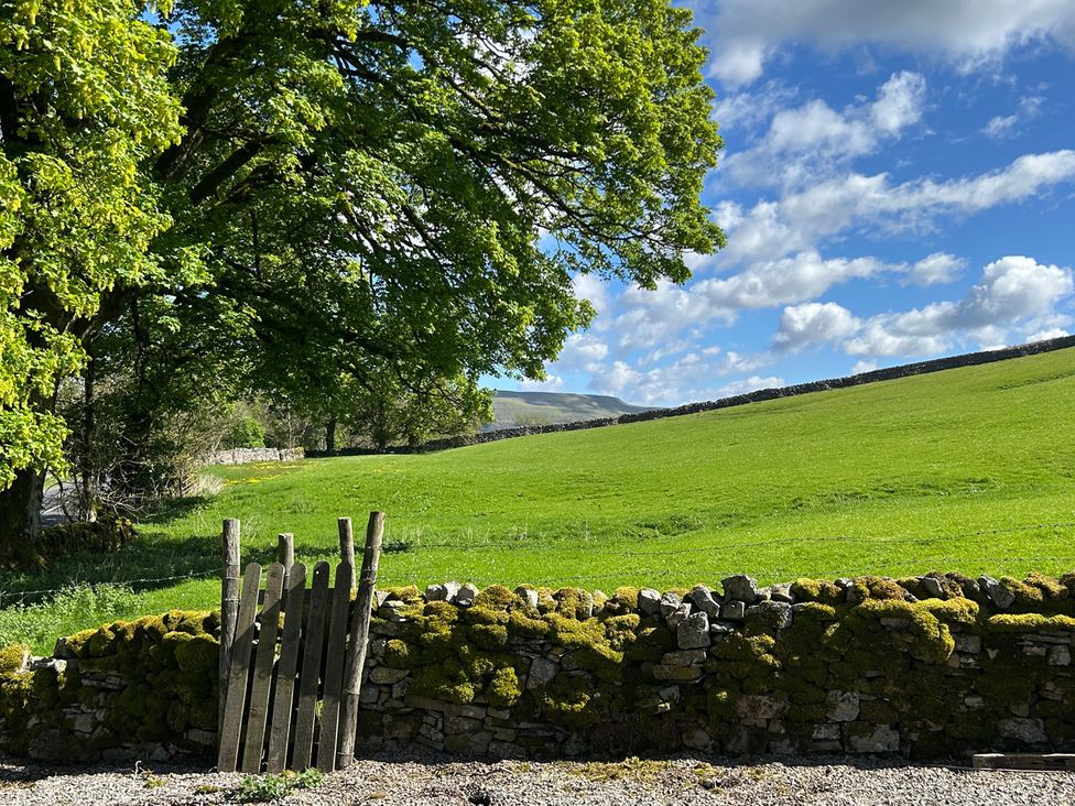 A field with a stone wall and wooden gate at Tarn House in Hawes