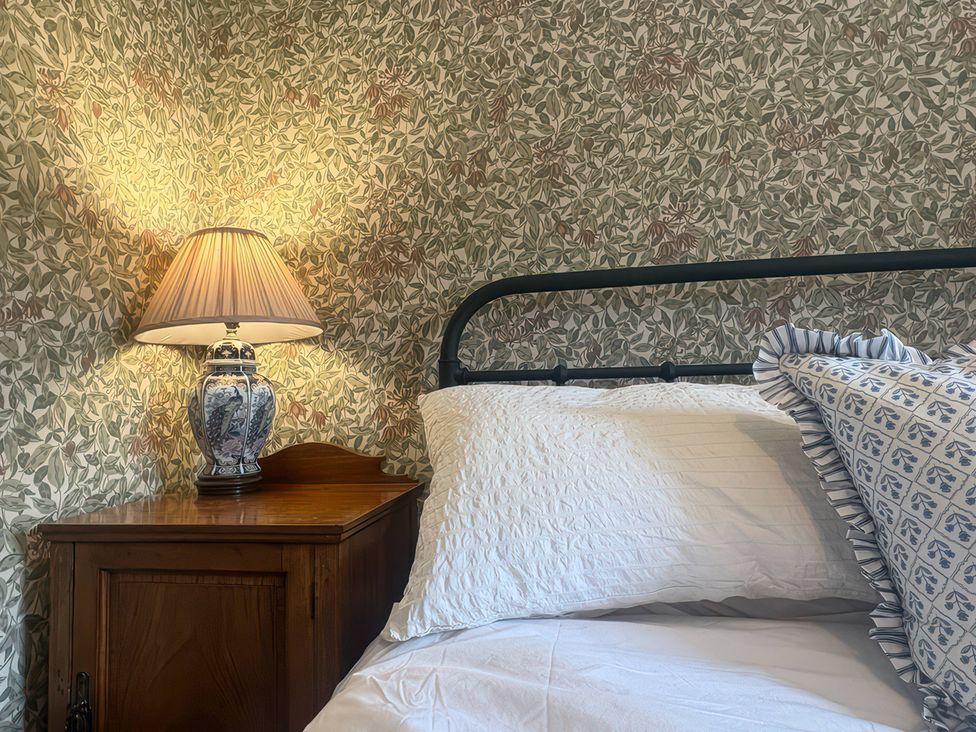A bedroom with a bed, lamp, and bedside table at Tarn House in Hawes