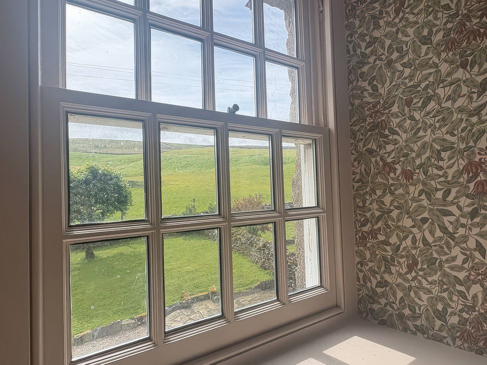 A window showing a view of grass and trees at Tarn House in Hawes