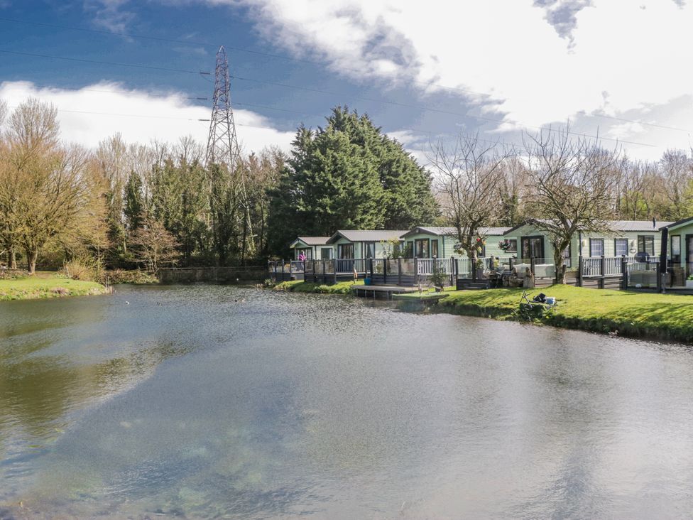 A view of cabins by a pond with trees at Carp Lodge