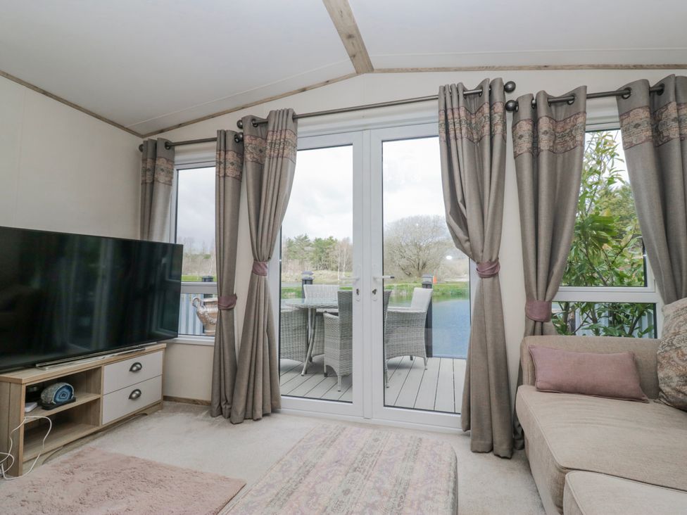 A snug with a television and patio doors at Carp Lodge
