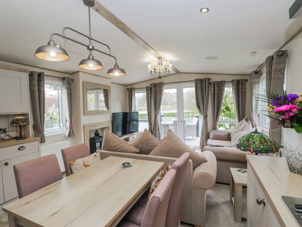 A living room with a dining area and television at Carp Lodge