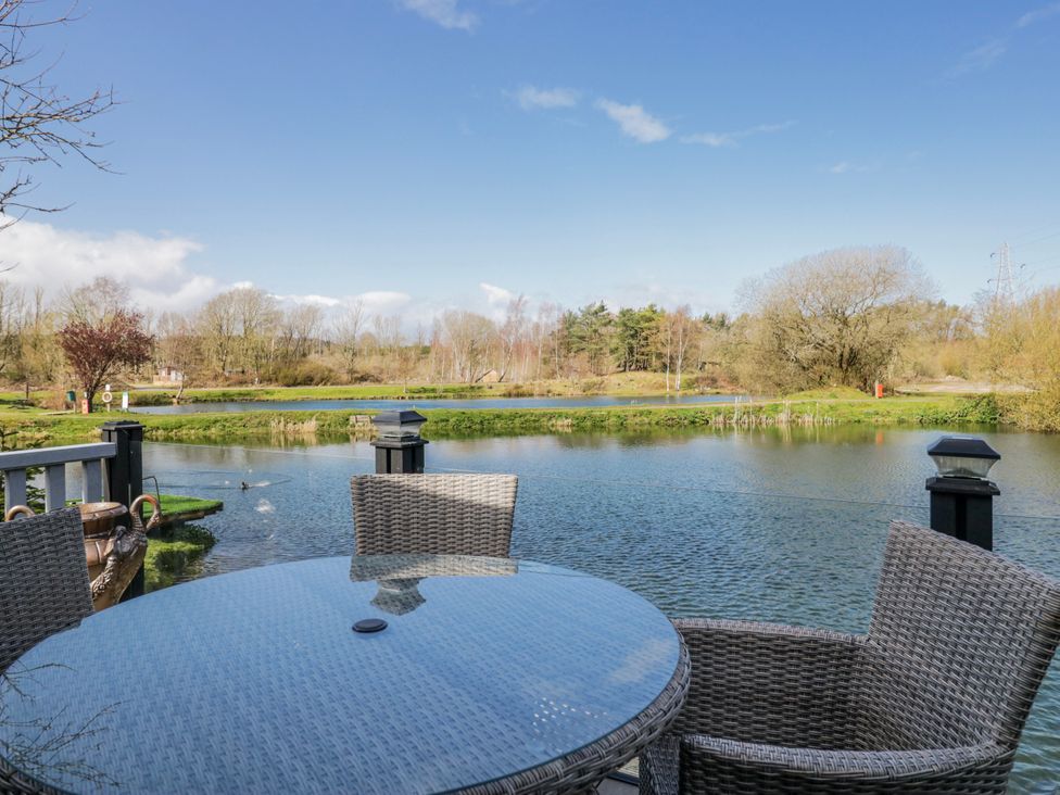 An outdoor area with a table and chairs overlooking a lake at Carp Lodge