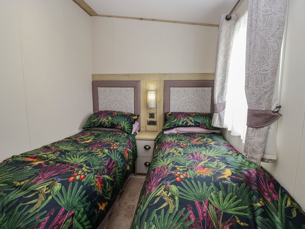 A bedroom with two beds and a bedside table at Carp Lodge near Carnforth