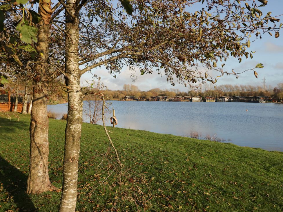 A view of a lake with trees and cabins at Carp Lodge near Carnforth
