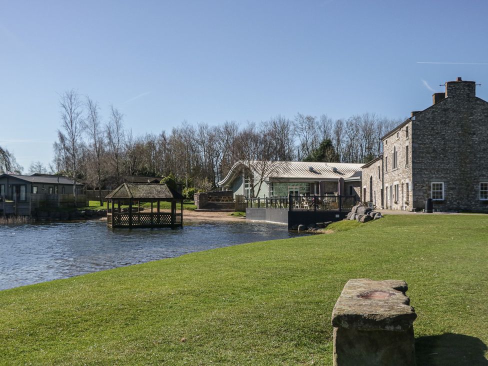 A view of a gazebo and buildings near water at Carp Lodge near Carnforth