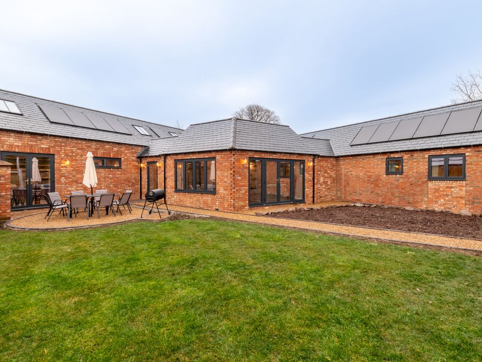 A garden with patio furniture and a house exterior at The Stables in Catworth