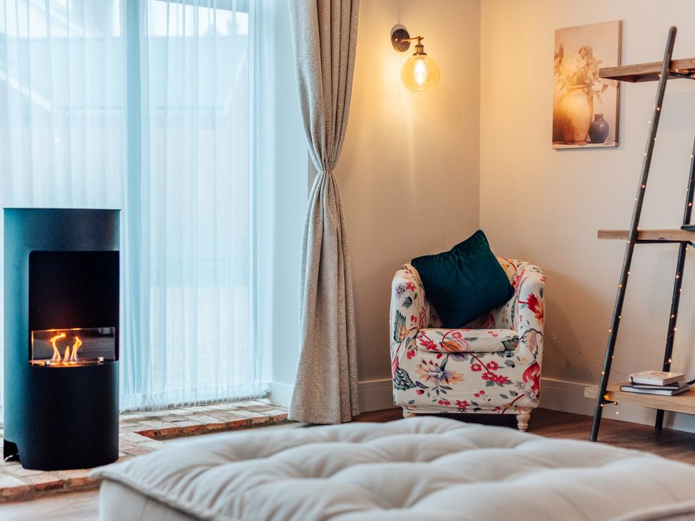A living room with an armchair and fireplace at The Stables in Catworth