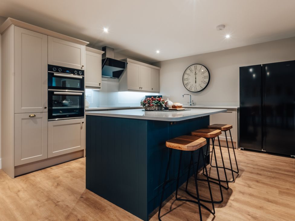 A kitchen with an island and stools at The Stables in Catworth