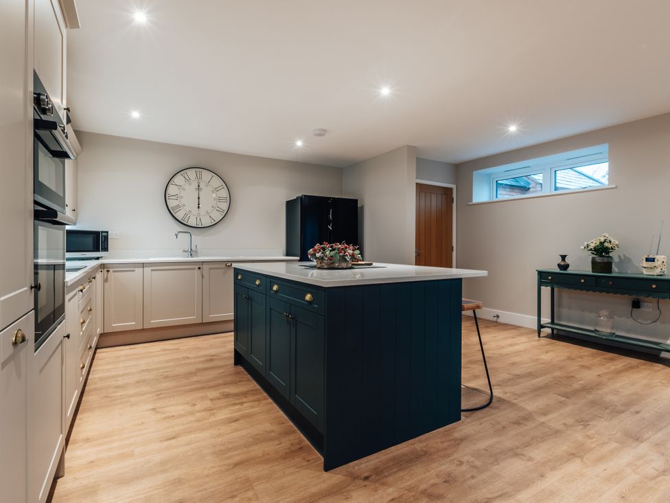 A kitchen with a refrigerator, oven and clock at The Stables in Catworth