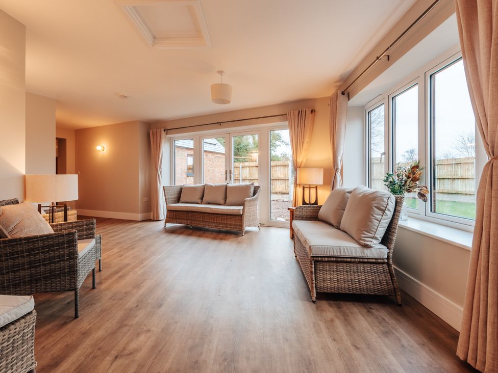 A snug with wicker furniture and large windows at The Stables in Catworth
