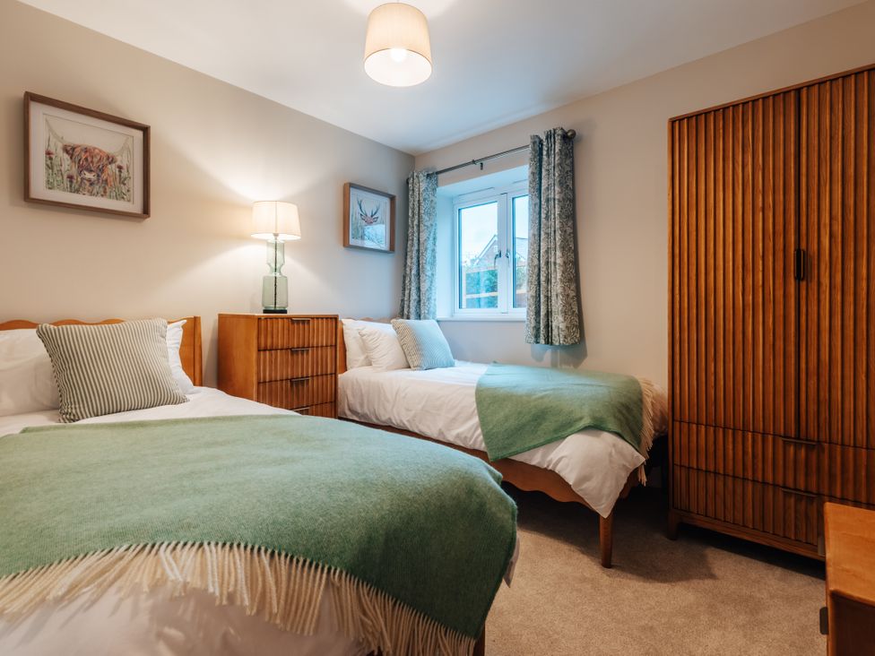 A bedroom with two beds and a wardrobe at The Stables in Catworth